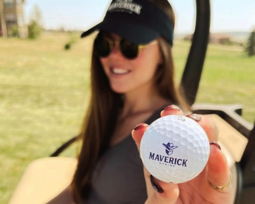Woman with glasses holding Maverick Gaming golf ball