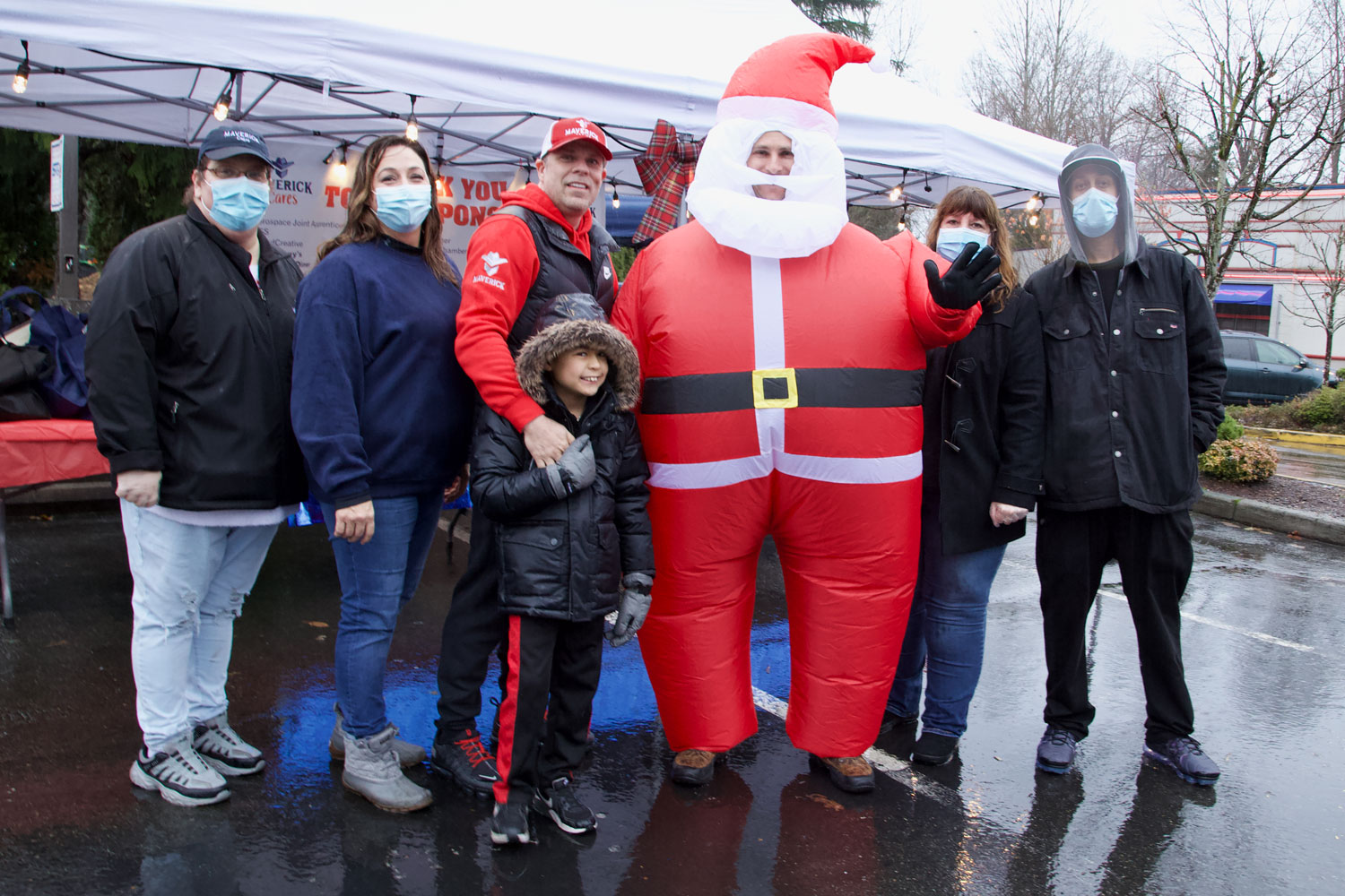 A group of people next to a man dressed like Santa Claus