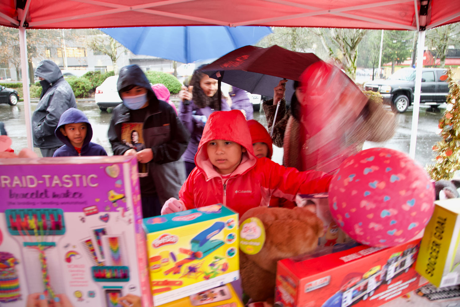 Kids with raincoats next to a table full of toys