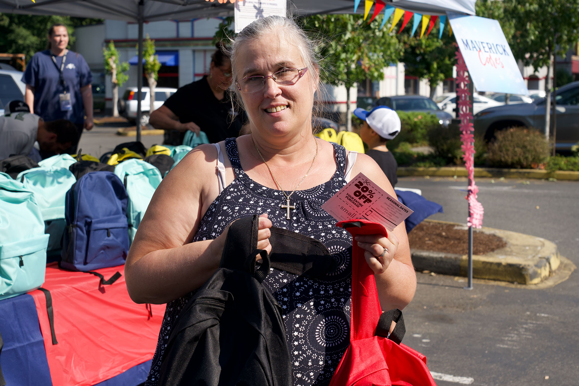 A woman with glasses holding a card and two backpacks