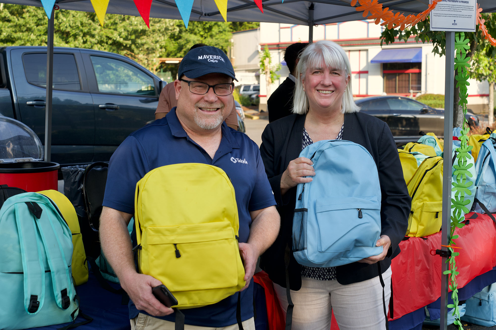 A woman and a man smiling holding backpacks