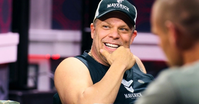 A man holding his chin smiling wearing a dark Maverick Gaming cap